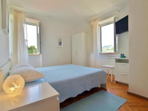 a bedroom with a bed and a desk and two windows at Rooms and Studio Old Town in Rab