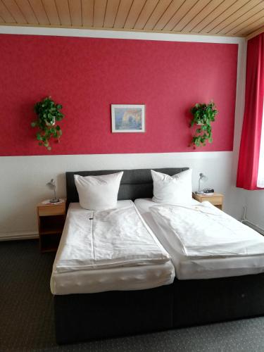 a bedroom with a large bed with a red wall at Hotel Am Stadtwall in Anklam