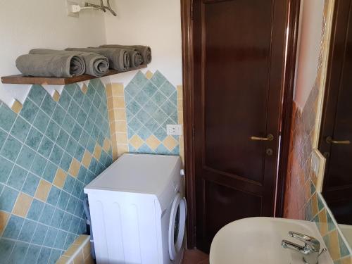 bagno con servizi igienici bianchi e parete piastrellata blu di Appartamento Monte Mare Arzachena a Arzachena