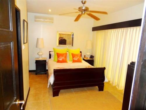 a bedroom with a bed with orange and yellow pillows at Brownes Condominium 2 in Bridgetown
