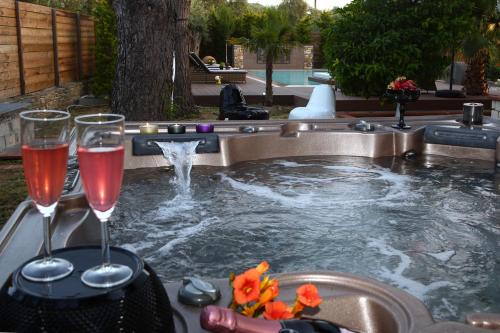 a pool with two glasses of wine and a fountain at Byblos Luxury Villa in Prinos