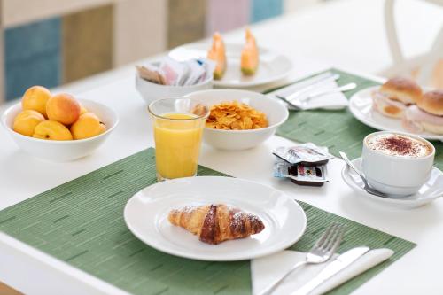 a table with plates of breakfast foods and a glass of orange juice at FAVIGNANA HOTEL Concept Holiday in Favignana