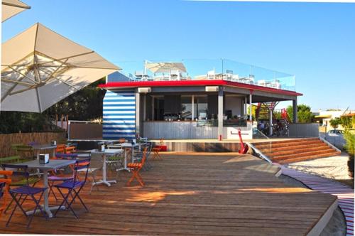 a deck with tables and chairs and a building at Hotel Intervallo in Torre Lapillo