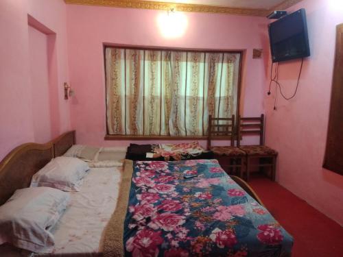 a bedroom with a bed and a television and a window at Hotel Jannat in Srinagar