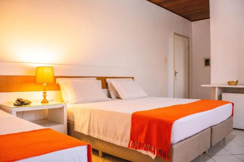 Hotel Terra do Sol في أراكاجو: غرفة فندقية بسريرين بملاءات برتقالية وبيضاء