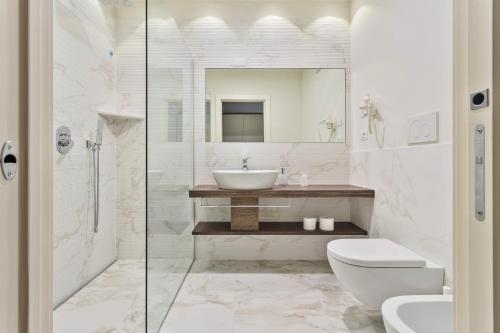 Baño blanco con lavabo y aseo en Hotel Gardesana, en Riva del Garda
