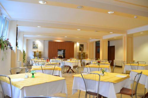 um restaurante com mesas brancas e cadeiras com toalhas de mesa amarelas em Casa Religiosa Di Ospitalità Nazareno em Spoleto