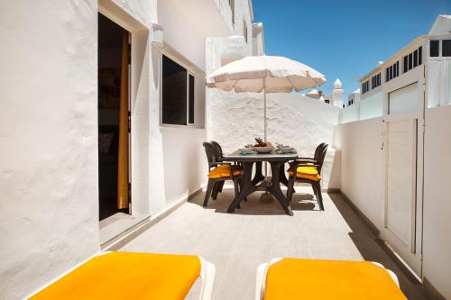 a patio with a table and chairs and an umbrella at Apartamento Victoria in Puerto del Carmen
