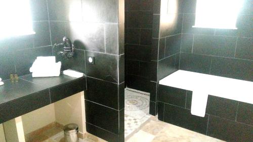 a black tiled bathroom with a sink and a toilet at L'hôtel du Couvent in Vagnas