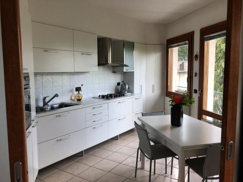 una cucina con armadi bianchi e tavolo con sedie di Appartamento Europa a Fanano