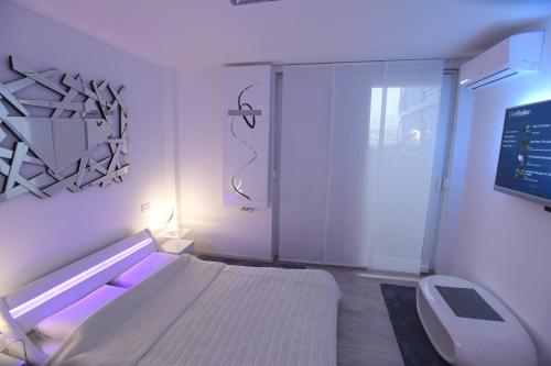 Dieses weiße Zimmer verfügt über ein Bett und einen TV. in der Unterkunft Apartment Wave -Luxury massage chair-Infrared Sauna, Parking with video surveillance, Entry with PIN 0 - 24h, FREE CANCELLATION UNTIL 2 PM ON THE LAST DAY OF CHECK IN in Slavonski Brod