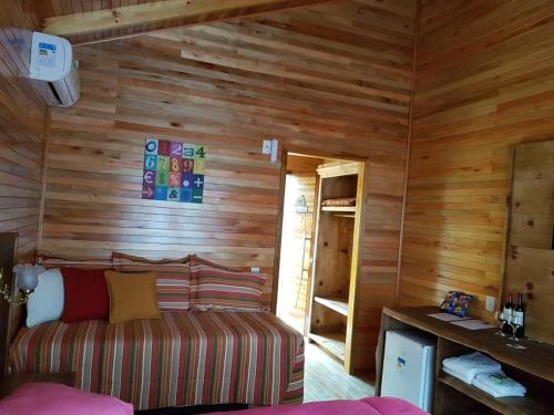 a room with a couch and wooden walls at Pousada Vila dos Butias in Urubici