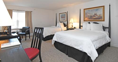 a hotel room with two beds and a desk at The Country Inn of Berkeley Springs in Berkeley Springs