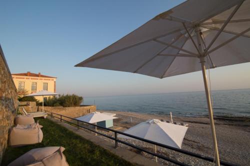 a row of tables and umbrellas on a balcony overlooking the ocean at Mare Studios Exclusive in Plomarion