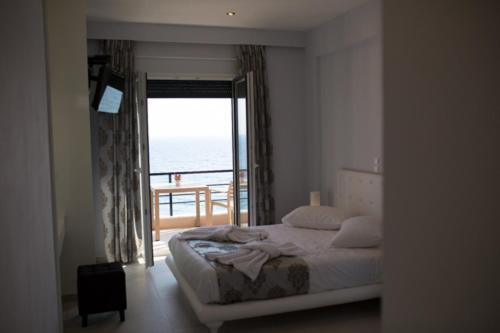 a bedroom with a bed with a view of the ocean at Mare Studios Exclusive in Plomarion
