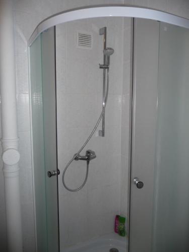 a shower in a bathroom with a glass door at White camomile condo in Šventoji