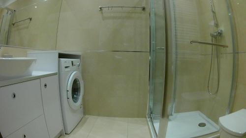 a bathroom with a shower and a washing machine at DUNE Apartments in Mielno