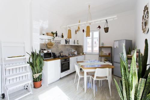 uma cozinha com armários brancos e uma mesa e cadeiras em La terrazza del Sole B&B em Palermo