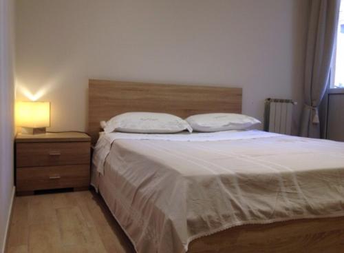 Schlafzimmer mit einem Bett mit einem Kopfteil aus Holz und einer Lampe in der Unterkunft Avaja Daria's apartment Taormina in Taormina