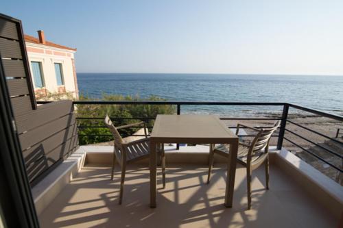a table and chairs on a balcony overlooking the ocean at Mare Studios Exclusive in Plomarion