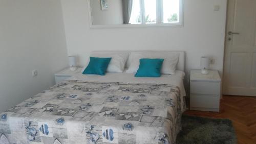 een slaapkamer met een bed met blauwe kussens bij Apartment Majić in Lovran