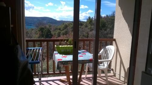 una mesa y sillas en un balcón con vistas en les Hauts du Lac en Sainte-Croix-du-Verdon