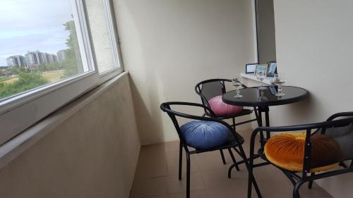 a small table and chairs in a room with a window at White camomile condo in Šventoji