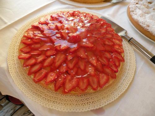 a cake with strawberries on a plate on a table at Hotel Parrini in Follonica