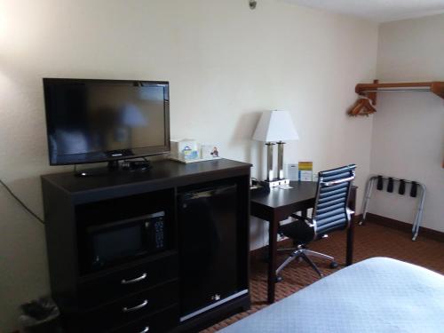 a hotel room with a television and a desk with a bed at Days Inn by Wyndham Hornell NY in Hornell