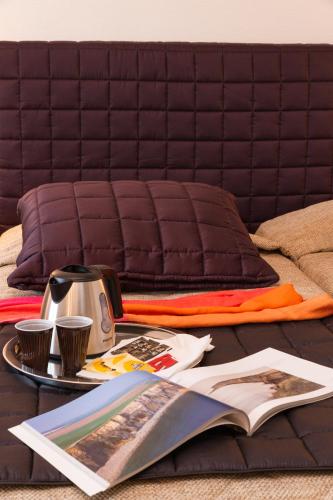 a bed with a table with a book and coffee cups at Hôtel L'ideal le Mountbatten in Arromanches-les-Bains
