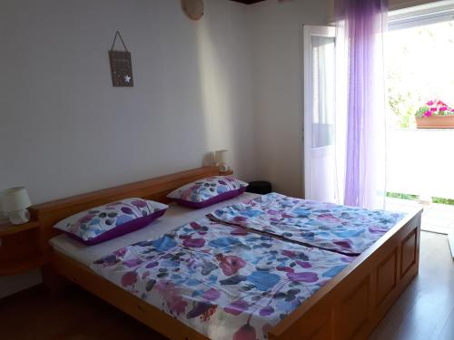 a bedroom with a bed with a floral comforter and a window at apartman Sanja in Rab