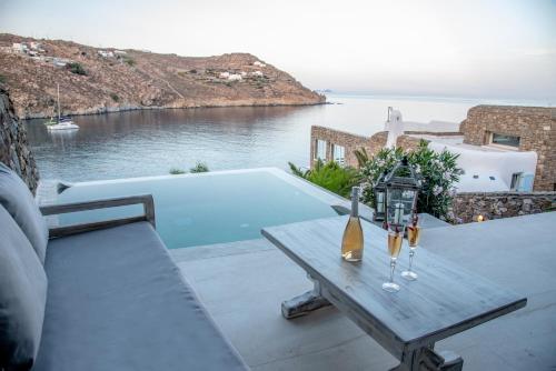 a wooden table with wine bottles and glasses on a patio at Etesians Suites & Villas in Super Paradise Beach