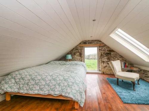 a bedroom with a bed and a chair in a attic at The Cowhouse in Carrick-on-Suir