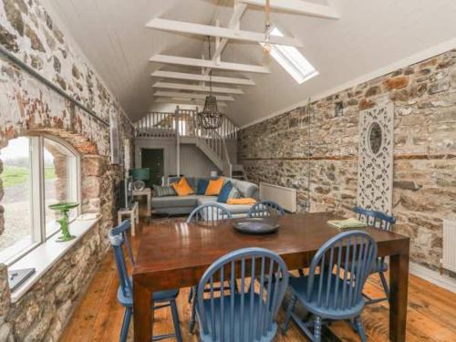 a dining room with a wooden table and blue chairs at The Cowhouse in Carrick-on-Suir