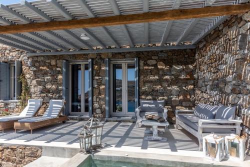 a patio with chairs and a stone wall at Etesians Suites & Villas in Super Paradise Beach