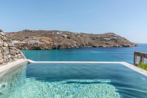a swimming pool with a view of the ocean at Etesians Suites & Villas in Super Paradise Beach