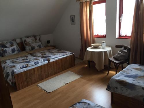 a bedroom with two beds and a small table with a table at Dósa tanya, Vendégház in Cserépfalu