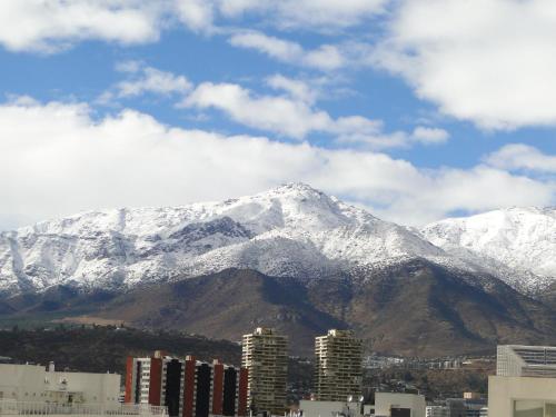 a mountain covered in snow in front of a city at Olea's Home Las Condes in Santiago