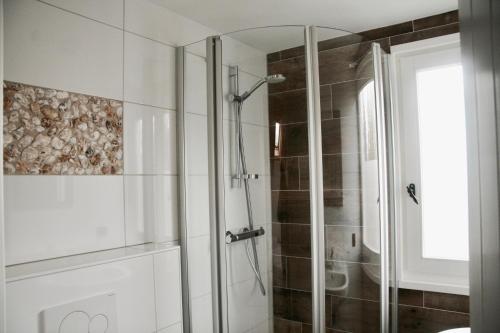 La salle de bains est pourvue d'une douche avec une porte en verre. dans l'établissement Bed & Breakfast Zeeland, à Renesse