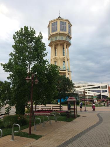 un bâtiment avec une tour d'horloge au milieu d'un parc dans l'établissement Mary Apartment, à Siófok