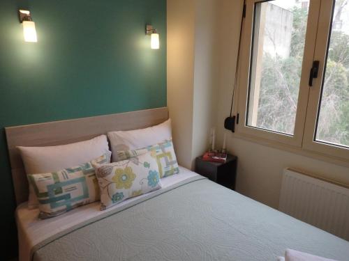 a bedroom with a bed with pillows and a window at Lion Apartment Sunset in Thessaloniki