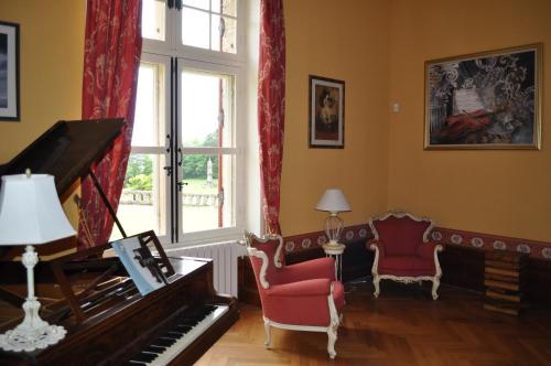 a living room with a piano and a chair at Château Logis de Roche in Clairac