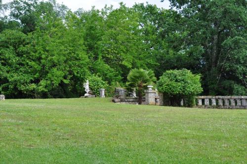 a field of grass with a fence and trees at Château Logis de Roche in Clairac