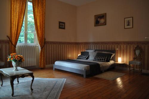 a bedroom with a bed and a table and a window at Château Logis de Roche in Clairac