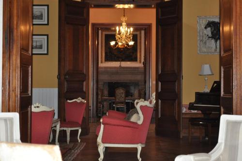 a living room with red chairs and a fireplace at Château Logis de Roche in Clairac