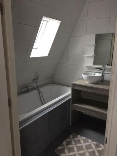 a bathroom with a sink and a tub and a mirror at Appartementen De Helling 44 in Heeg