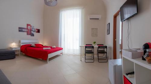 a bedroom with a red bed and a table with stools at Enjoy Trani in Trani