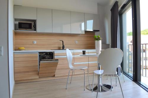 a kitchen with white chairs and a table and a counter at Apartament Horyzont 405 Międzyzdroje in Międzyzdroje