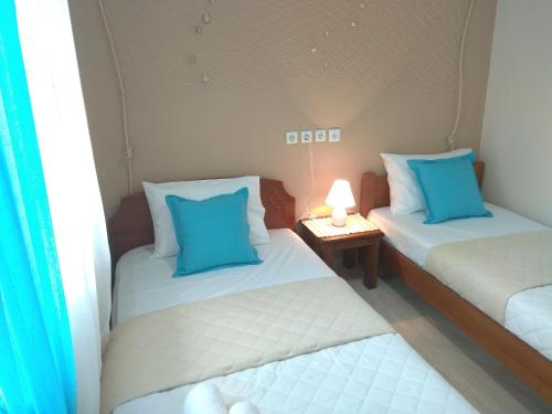 two twin beds with blue pillows in a room at Skiron House in Skala Kallirachis
