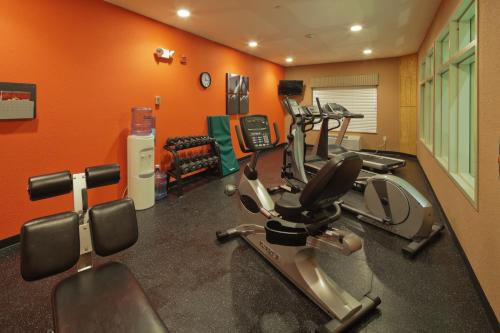 a gym with cardio equipment in a room with orange walls at Country Inn & Suites by Radisson, Madison Southwest, WI in Fitchburg
